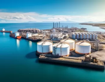 Aerial view of an industrial port with large cylindrical storage tanks.