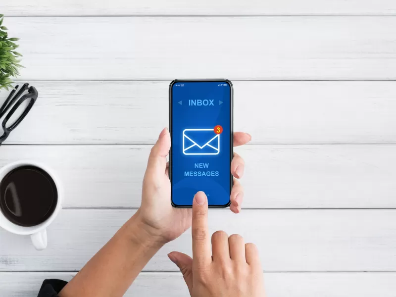 A persons hand with a smartphone showing an email icon, illustrating the concept of modern communication technology.